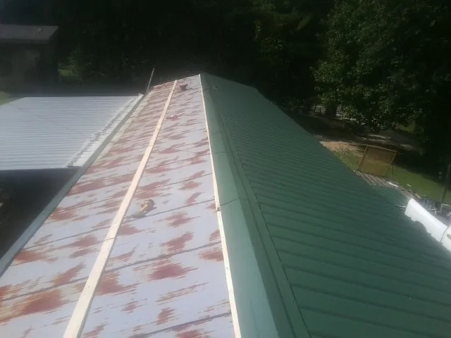 Old rusted panels beside newly installed green metal roofing — Wind Damage Roof Repair by Roofing Brothers in Honeyville