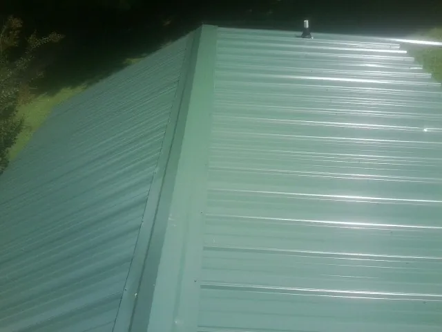 New green metal panels meeting at the ridge of a roof — Flat Roof Repair work by our crew in Honeyville