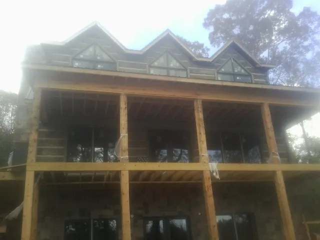 Dormers and porch framing on a large log home under construction — Roof Coating work by our crew in Honeyville