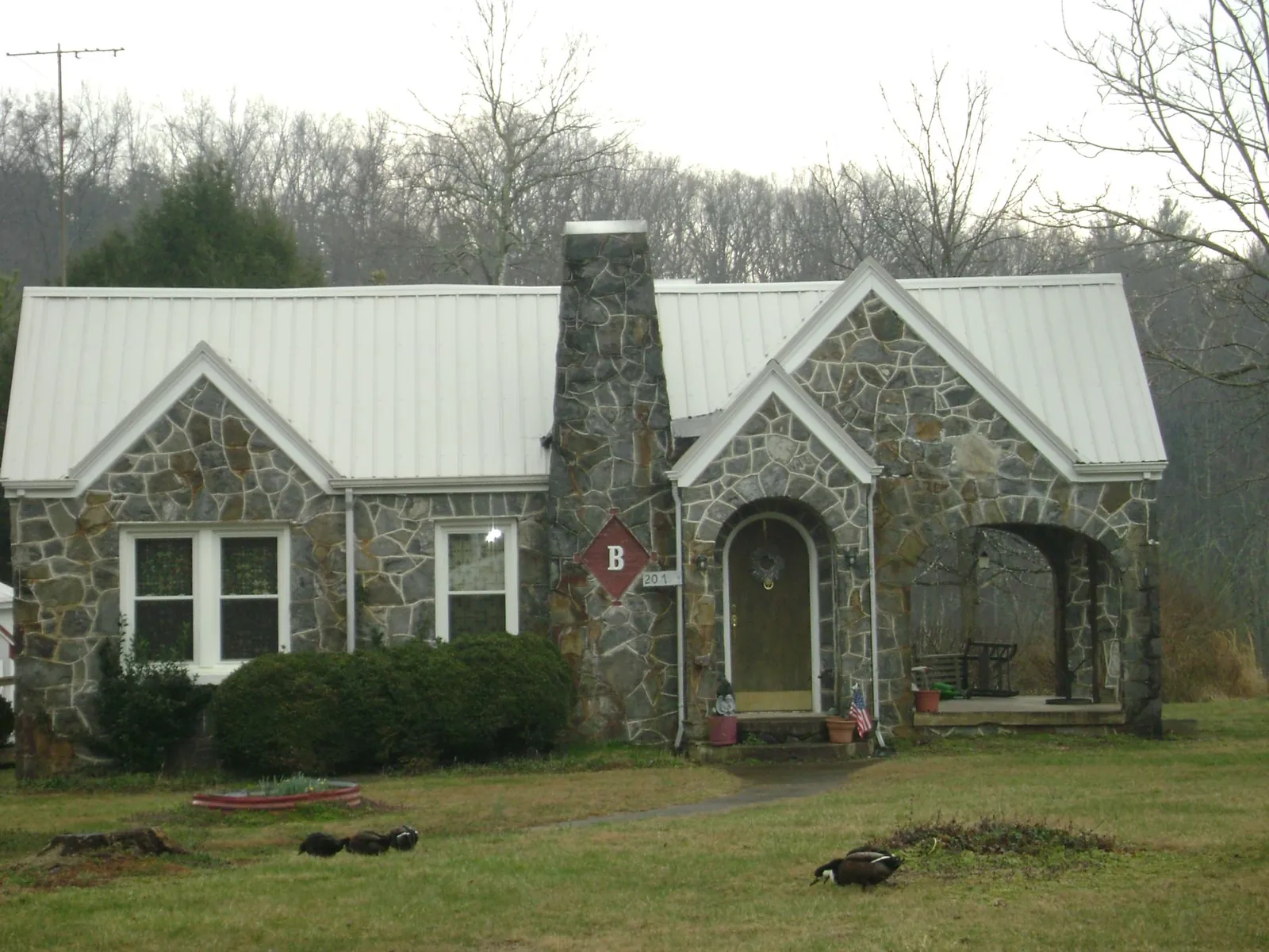 White metal roof on a stone cottage with steep gables in Honeyville