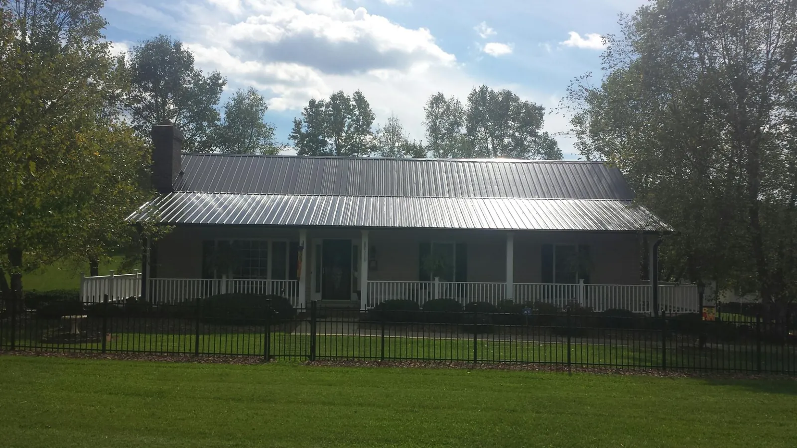 Gray metal roof on a brick ranch with a full width front porch — Gutter Guard Installation work by our crew in Honeyville