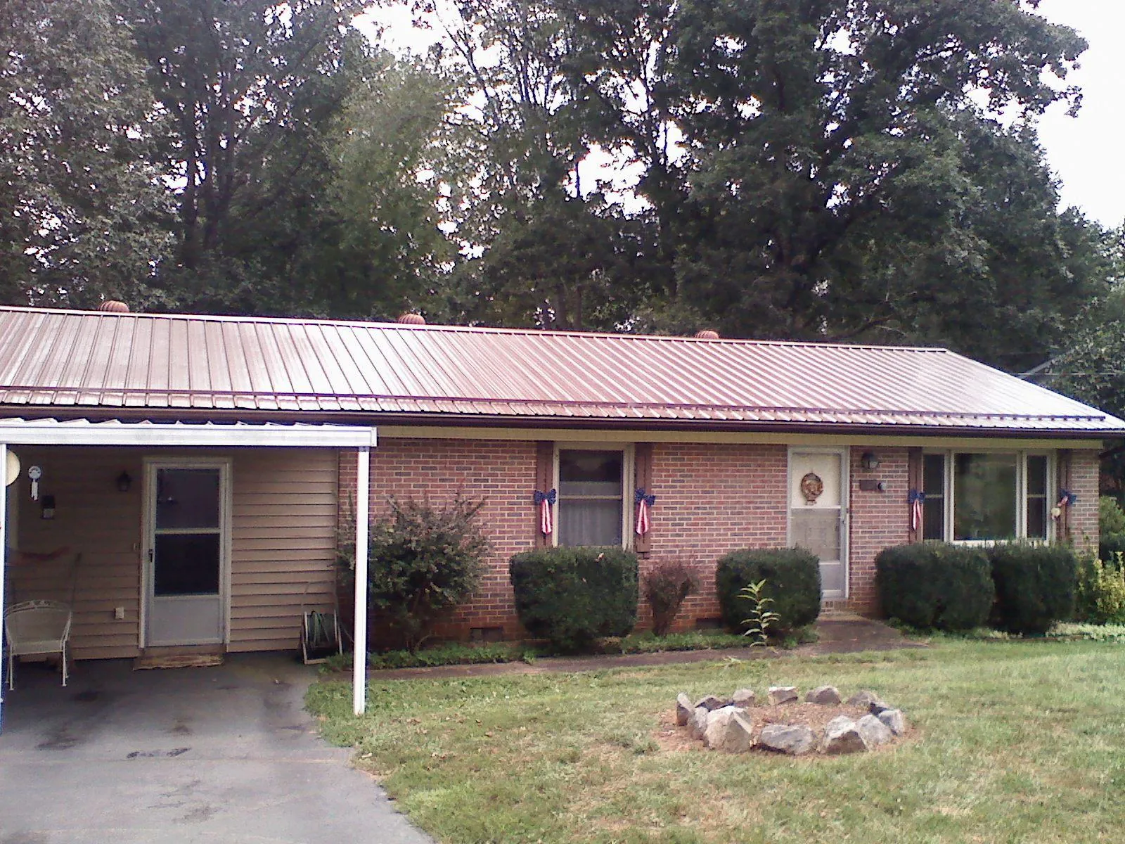 Bronze metal roof and carport on a brick ranch home — Roof Repair work by our crew in Honeyville