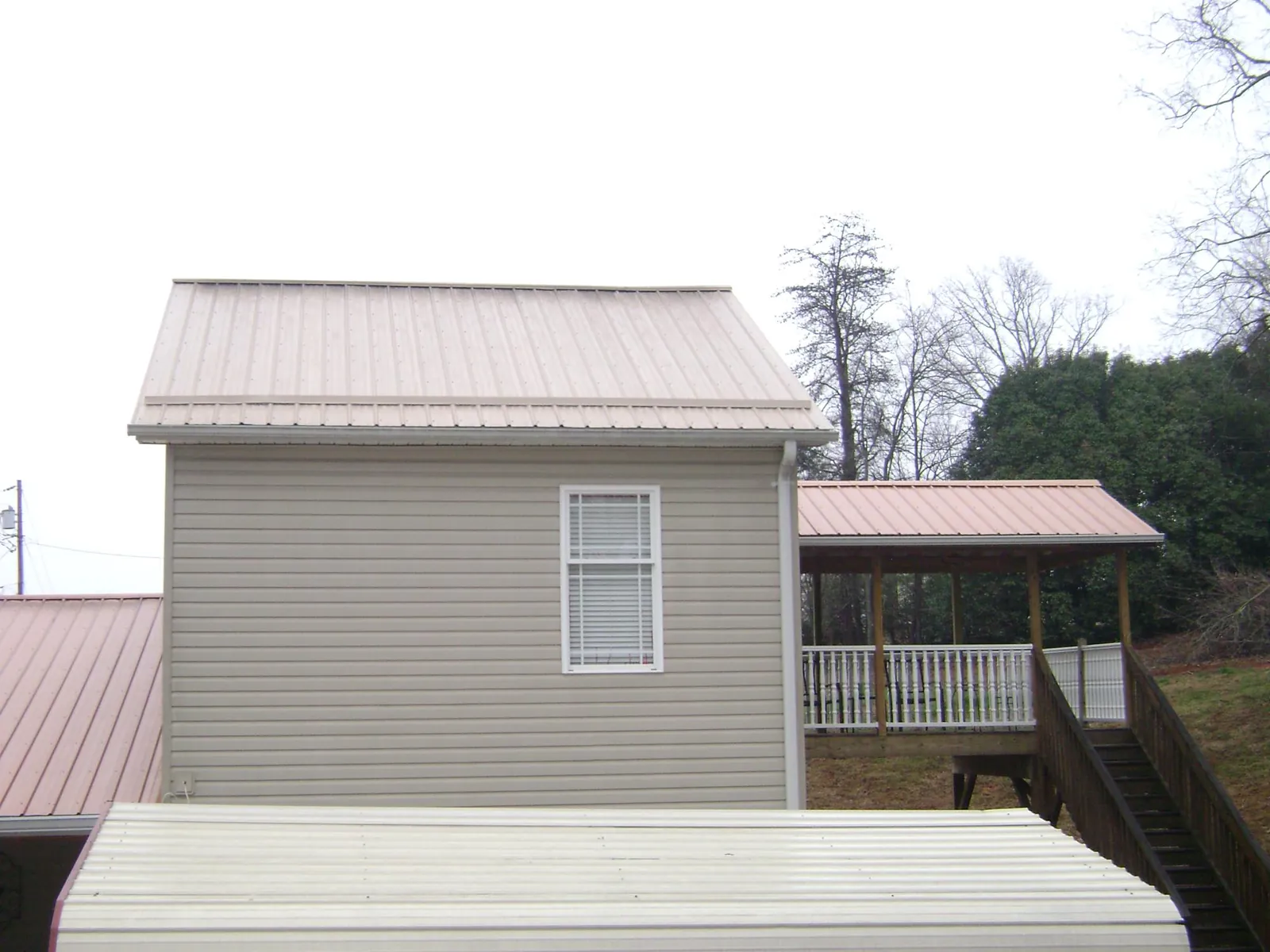 Tan metal roofs on a two story addition and attached porch, from a Roof Replacement job in Honeyville