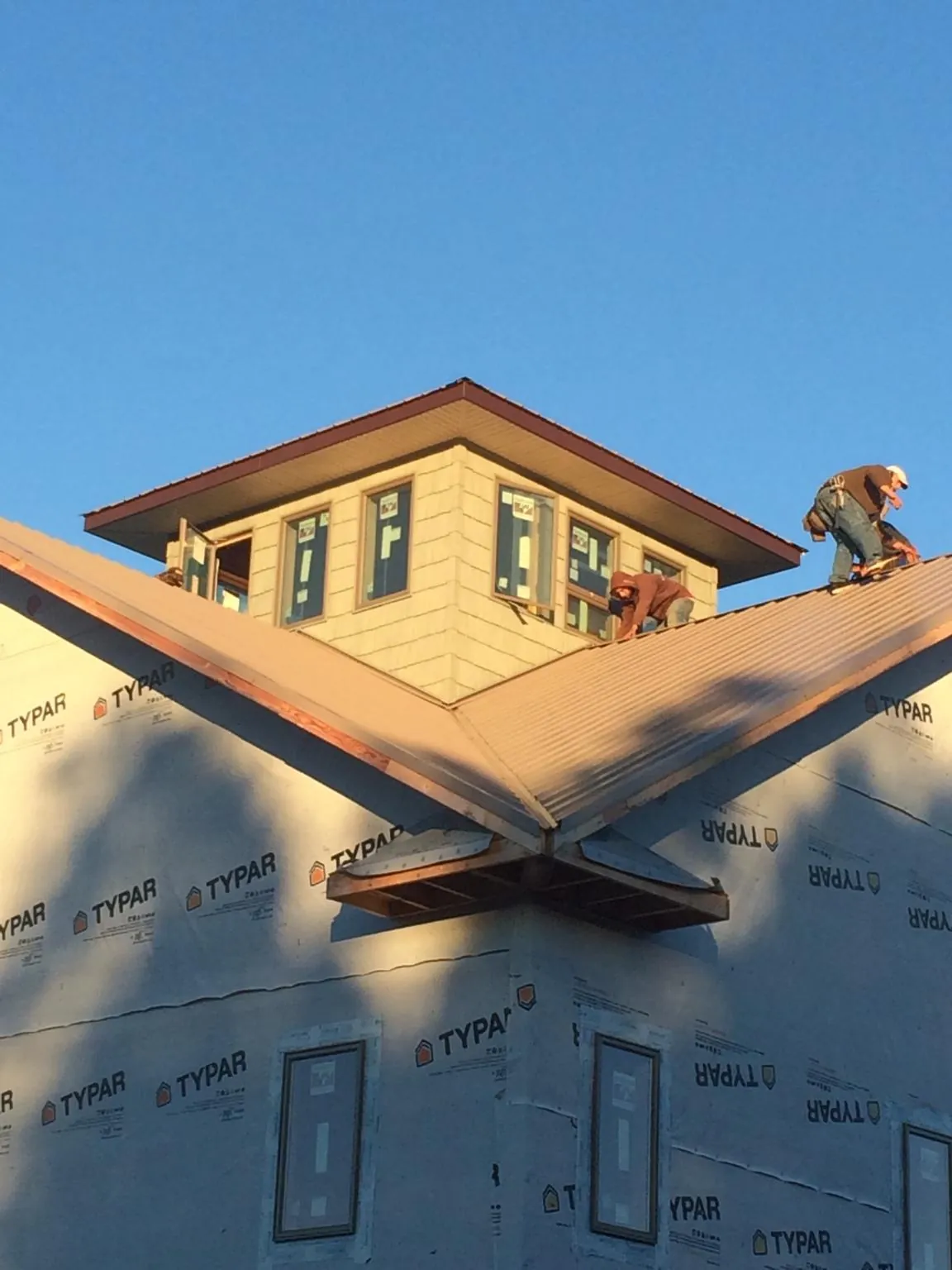 Roofers working around a rooftop cupola on a new metal roof at sunset — Roof Waterproofing in Honeyville by Roofing Brothers